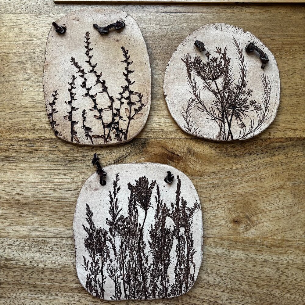 VINTAGE SET OF THREE CLAY PLAQUES WITH BOTANICAL IMPRINTING LEATHER HANGERS